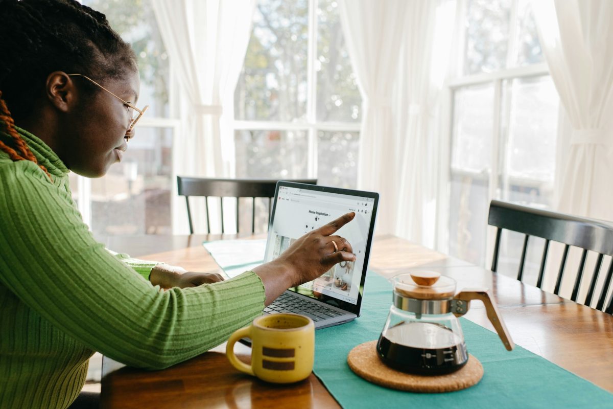 Woman using a touchscreen laptop at a table beside a window