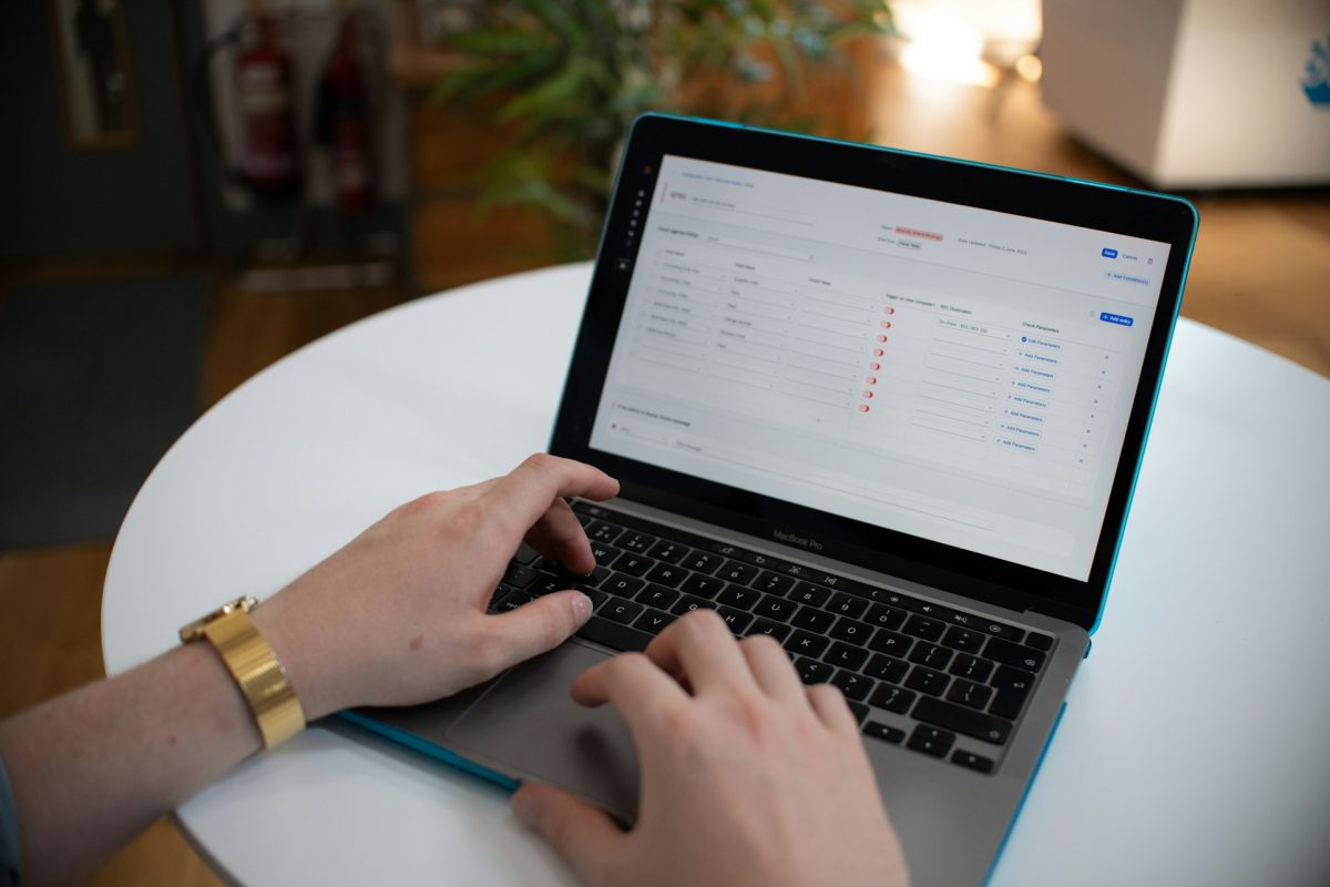 Hands using a laptop displaying a table of records